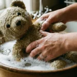 A close up view of a soft toy receiving gentle hand washing